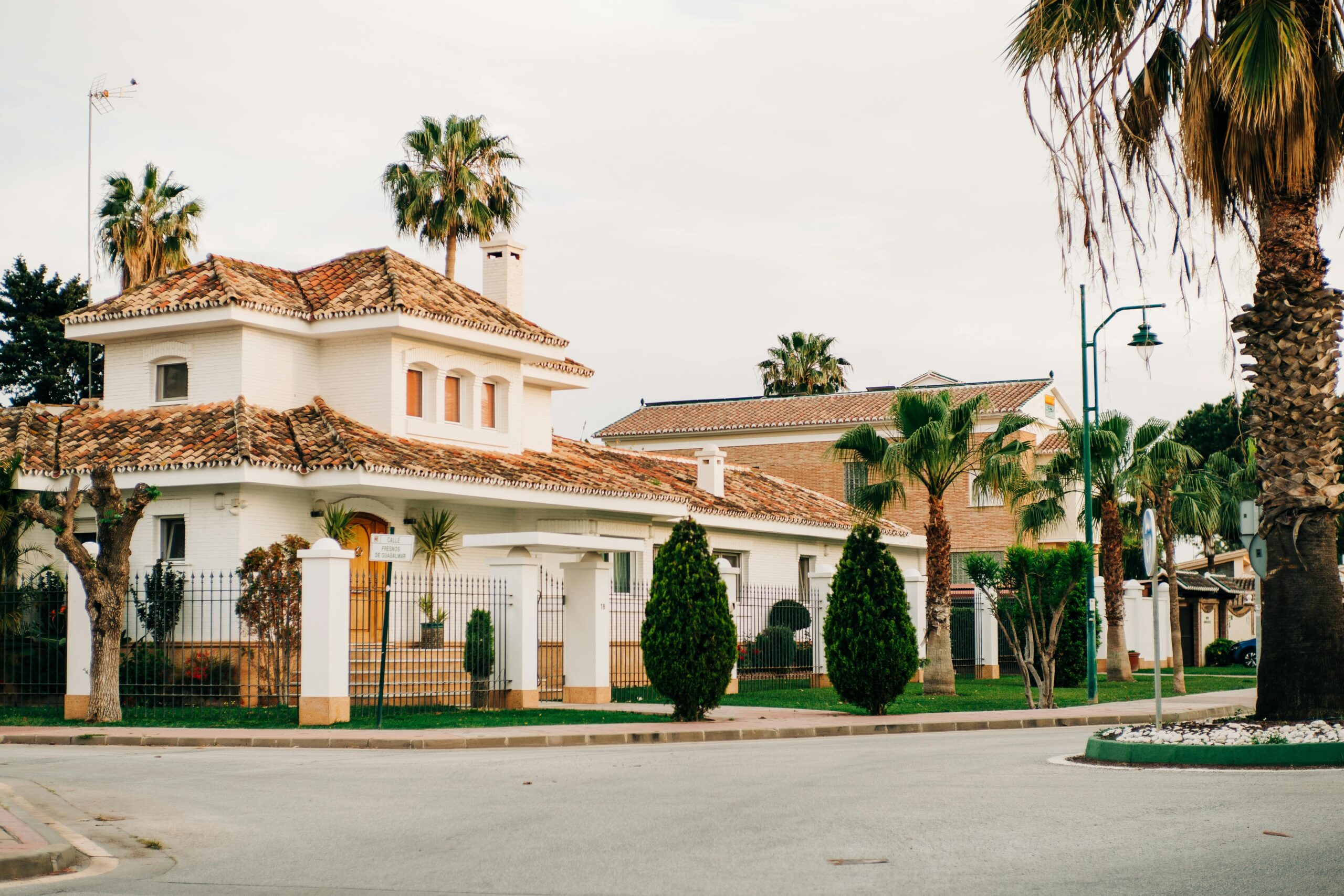 Charming villas with Mediterranean architecture in Málaga, Spain, lined with palm trees.